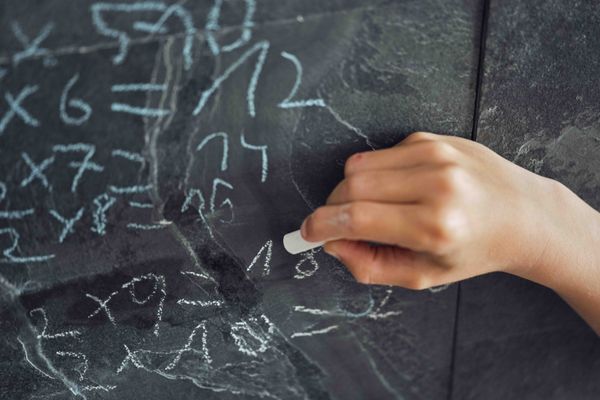 A child is writing on a chalkboard - mastering the art of passing mathematics.