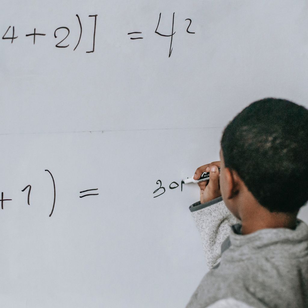 A child learning maths on a whiteboard, for their future career in Engineering