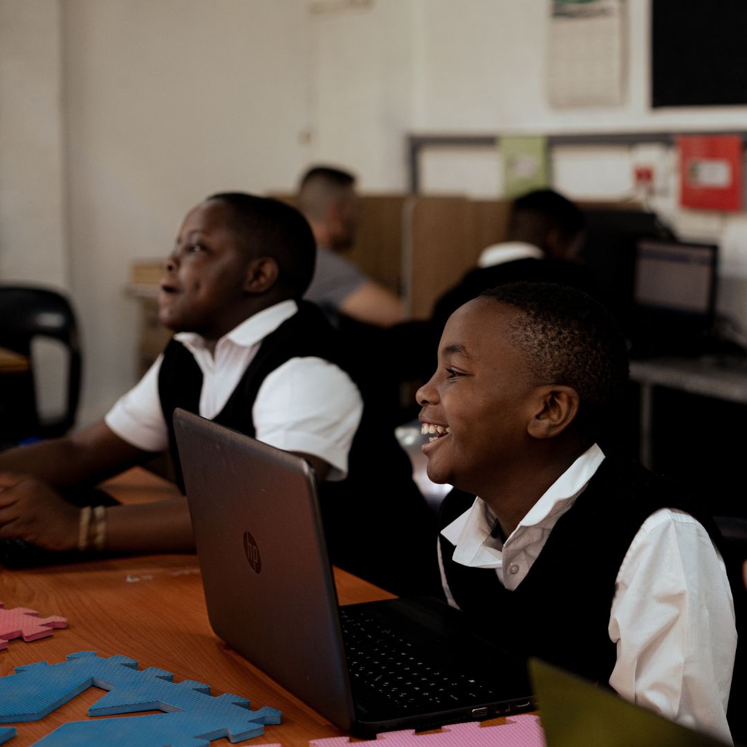 A cheerful student is learning about Grade 6 life orientation via a laptop in class.