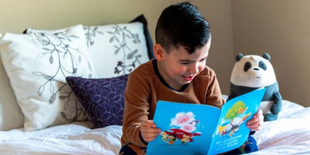 A boy is smiling as he reads a book.