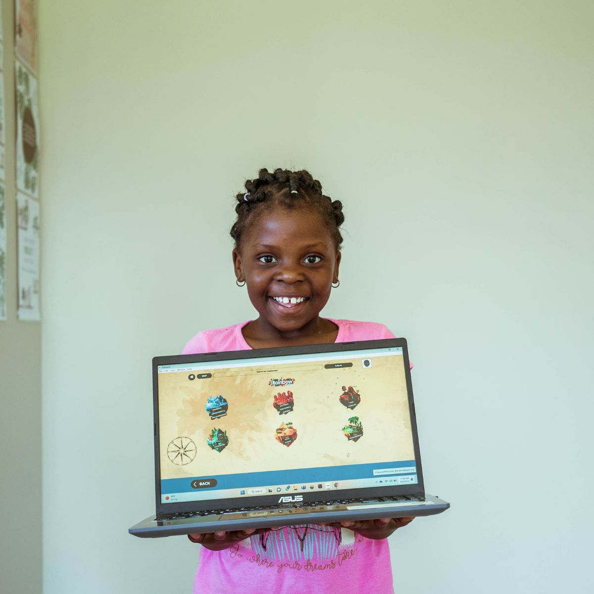 A child smiling, holding a laptop with iRainbow’s educational English software.
