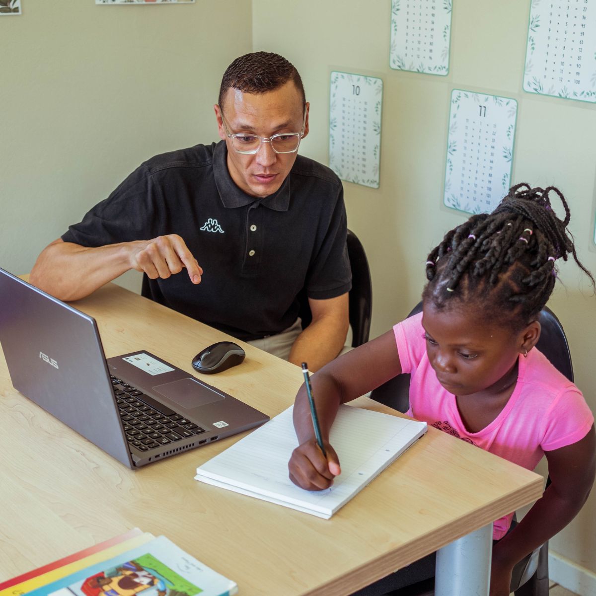 A learner using a laptop and notepad to learn grade 5 English with iRainbow’s educational software.
