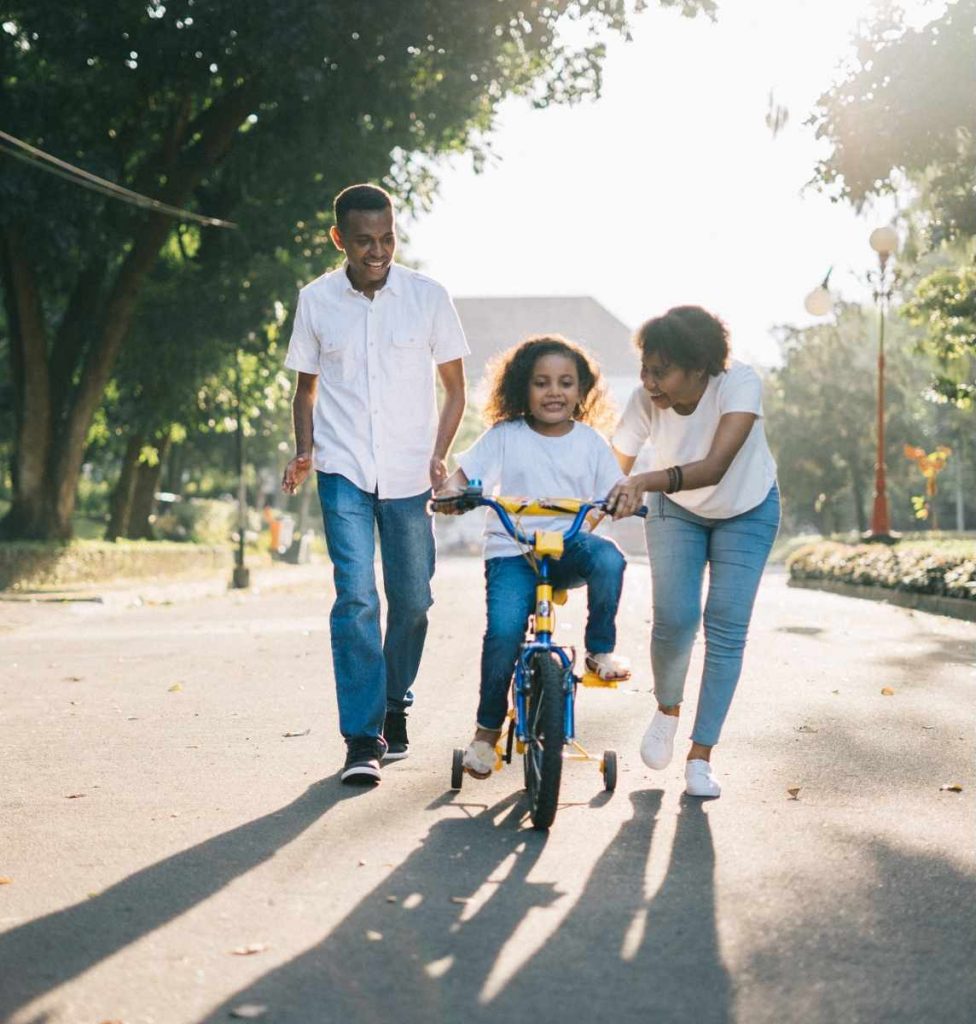 Parents helping their child exercise by riding a bicycle, managing stress